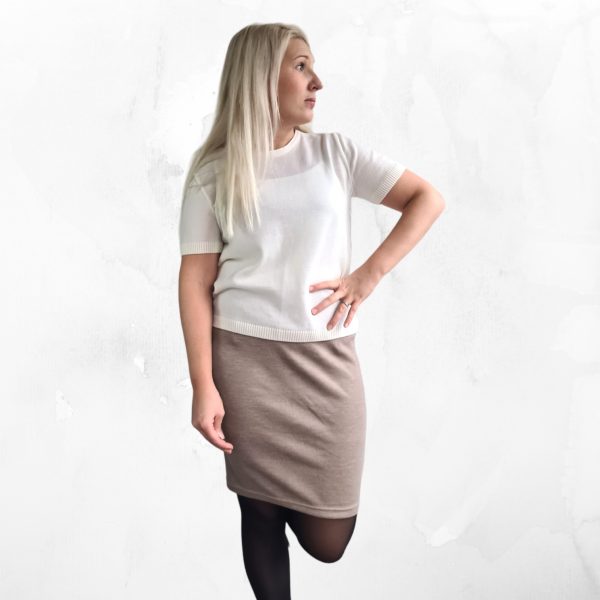Sara merinovillahame taupen värisenä kuvattuna suoraan edestä mallinpäällä. Mallilla on valkinen paita ja vasenkäsi lanteella.